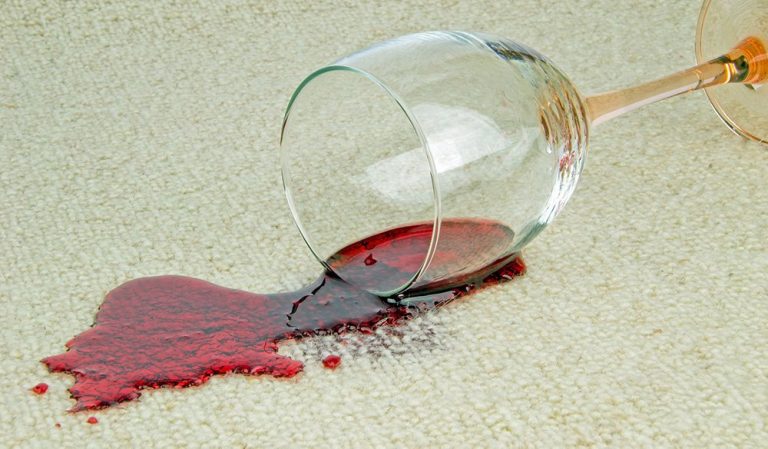 A spilled glass of red wine on a carpet